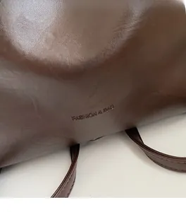 Close-up of dark brown leather bucket bag with fashion & bag embossed logo detail