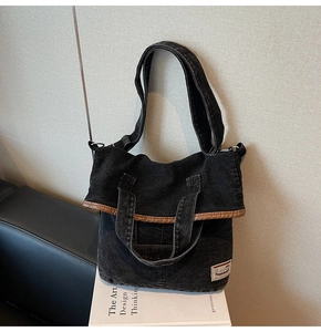 Detail of a black denim tote bag with brown leather trim and xiuxian fabric label