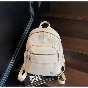 Close-up of beige faux leather backpack with litchi texture and metal ring zippers