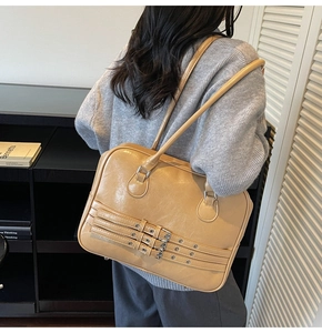 Model wearing a large khaki vintage tote bag with decorative silver buckle straps