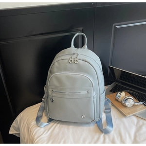 Detailed macro view of light grey pebble leather backpack with light blue straps