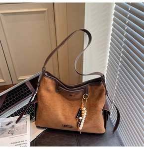 Detailed macro view of brown suede tote bag featuring ethnic bead charm and leather trim