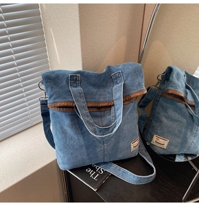 Detail of blue denim tote bag featuring vintage leather trim and woven brand label