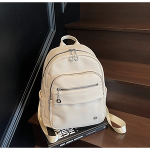 Detail of off-white faux leather backpack with litchi texture and silver metal zippers