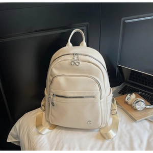 Detail of cream backpack showing lychee leather texture and silver circular zipper pulls