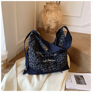 Close-up of leopard print denim hobo bag with artistic lettering and bow detail