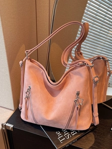 Pink matte suede tote bag with star charms and adjustable straps on black books