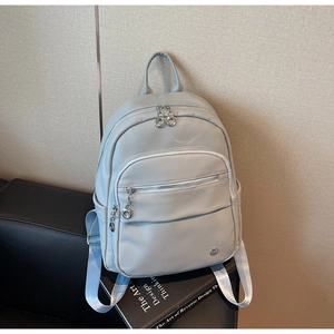 Detail view of large capacity leather backpack with multiple pockets and silver zippers