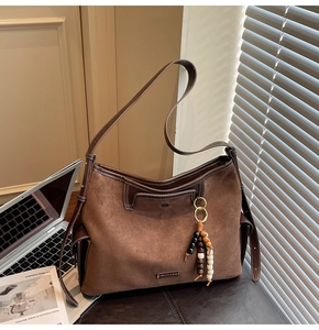 Detail of dark brown suede hobo bag with wooden bead tassel and side flap pocket
