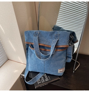 Detail of blue denim tote bag with brown leather trim and stylish woven label detail
