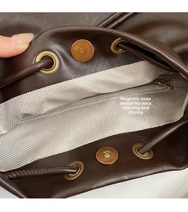 Detail of magnetic buckle and drawstring closure on brown leather bucket bag