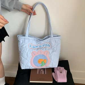 Detail of light blue heart-quilted tote bag featuring cartoon fish embroidery and text
