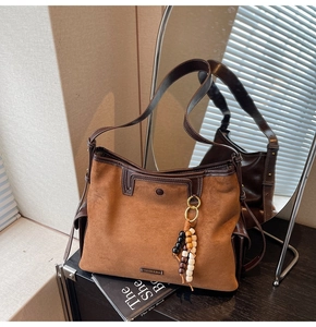 Detail of vintage brown suede tote bag with leather trim and wooden bead tassel accessory