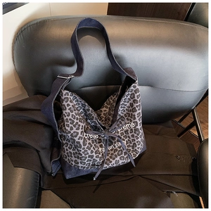 Detail of leopard print canvas bag with denim trim and adjustable metal buckles