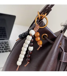 Detail of bohemian wood bead charm with gold metal ring on a brown leather bucket bag