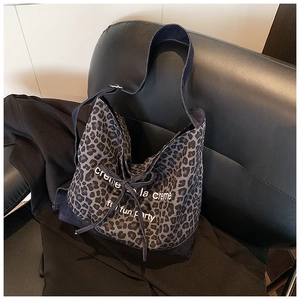 Detail of leopard print tote bag featuring a drawstring closure and cream text on canvas