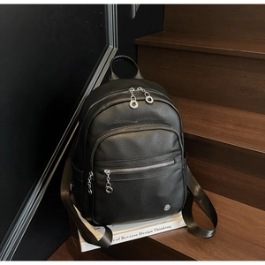 Detail of premium black lychee pattern backpack with silver metal zippers on wooden stairs