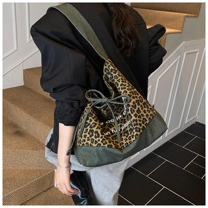 Detail of leopard print denim hobo bag with dark green trim and drawstring cord