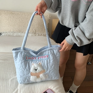 Detail shot of light blue quilted tote bag with cute plush puppy embroidery on a model