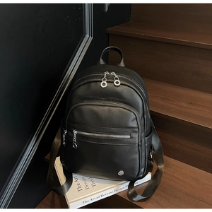 Detail of black pebbled leather backpack with silver zippers and multi-pocket design
