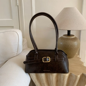 Detail van donkerbruine vintage mat leren tas met gouden gesp op een bijzettafel