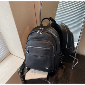 Detail of black lychee grain leather backpack with dual zippers and circular metal logo