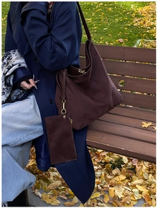 Detail of coffee brown suede tote bag with matching pouch on an outdoor wooden bench