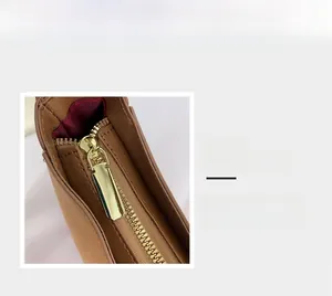 Détail montrant une fermeture éclair en métal doré et un tissu en daim mat marron
