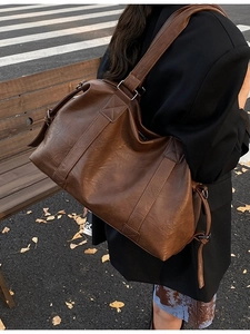 Large brown leather tote bag with wide shoulder strap for women shown in street style