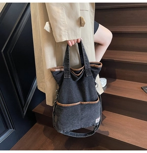 Detail of black washed denim tote bag with leather piping on wooden stairs
