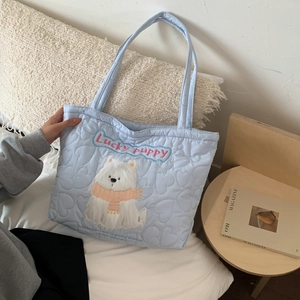 Detail of light blue quilted tote bag with heart patterns and lucky puppy embroidery