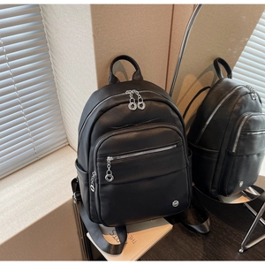 Close-up of black lychee grain leather backpack with circular metal zipper pull details