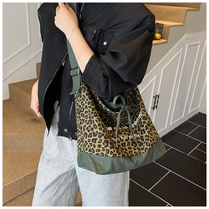 Detail of leopard print canvas tote bag with drawstring closure and green contrast straps
