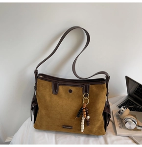 Macro shot of ginger suede tote with dark leather trim and colorful bead tassel accent