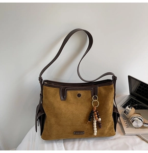 Close-up of brown suede tote bag with leather trim and wooden bead charm detail