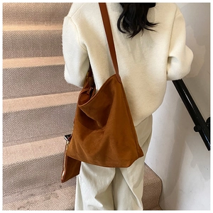 Brown suede hobo bag with matching small zipper pouch shown on person on stairs