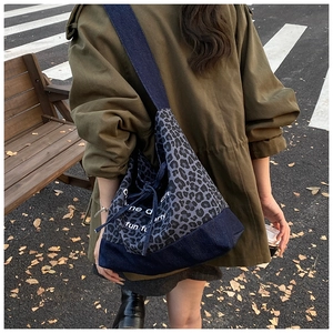 Detail view of leopard print tote bag featuring denim stitching and drawstring closure