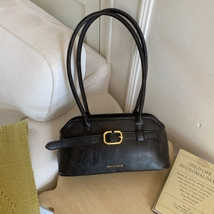 Detailopname van zwarte vintage leren hobo tas met gouden gesp en reliëflogo