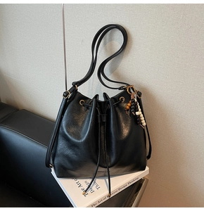 Close-up of black drawstring bucket bag with colorful beads on a leather sofa