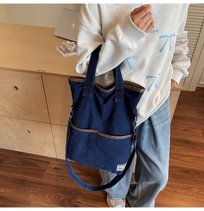 Detail showing deep blue denim tote bag with brown leather piping and dual front pockets