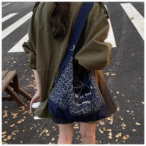 Detail of leopard print denim tote bag showing side lettering and adjustable drawstring