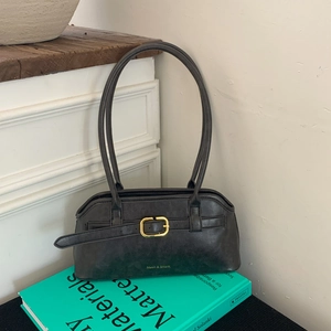 Detail van vintage zwarte leren tas met gouden gesp en logo op een houten tafelblad