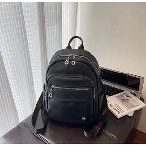 Close-up of a black pebbled leather backpack with metal ring zipper and side pockets