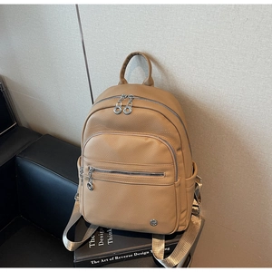 Detailed macro view of khaki leather backpack texture with silver zipper and logo emblem
