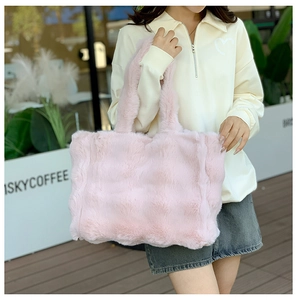 Vista detallada de un bolso tote de peluche rosa con correas anchas y textura de piel sintética