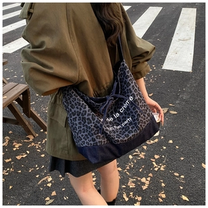 Detail of large leopard print tote bag in dark blue denim canvas with white text print