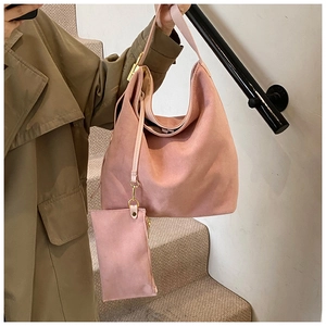 Detail of matte suede tote bag in dusty rose featuring a matching zipper pouch and gold hardware