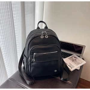 Detailed macro of black pebbled leather texture and silver chain zipper on stylish backpack