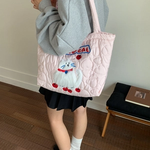 Detail of pink quilted tote bag featuring white cat embroidery and heart pattern