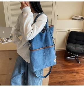 Detail of blue denim tote bag with brown leather trim shown in a cozy office setting